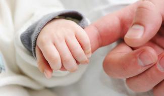Image of an infant holding an adult's finger